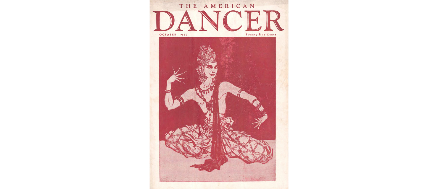 An illustration in shades of red shows Indian dancer Uday Shankar in performance, crouching low to the ground with an upright torso, fingers splayed in intentional mudras as he glances toward the viewer from the corner of his eye. In the same red as the background is written, "The American Dancer, October, 1933, twenty-five cents."