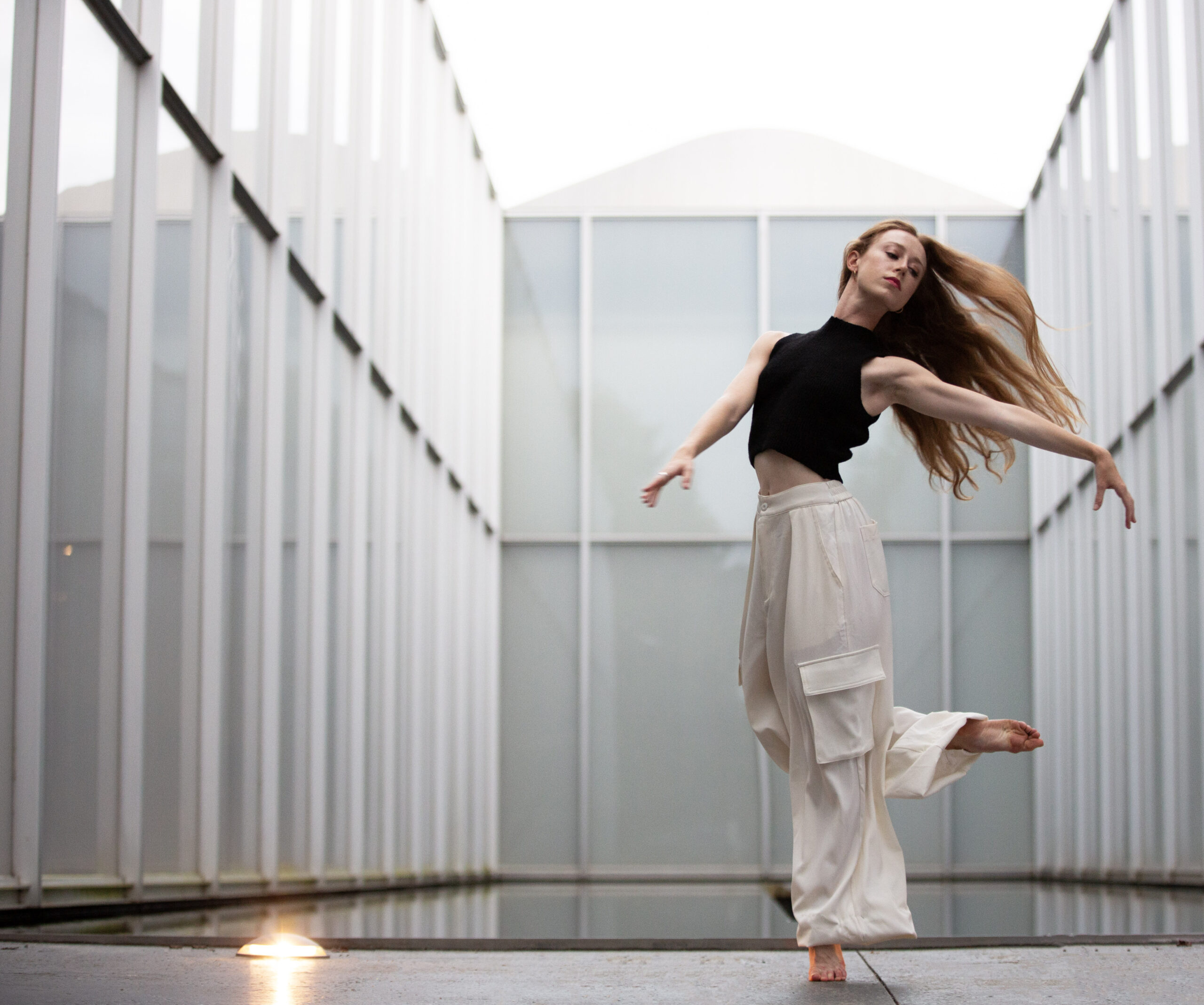 a female dancer wearing white pants dancing in a white room