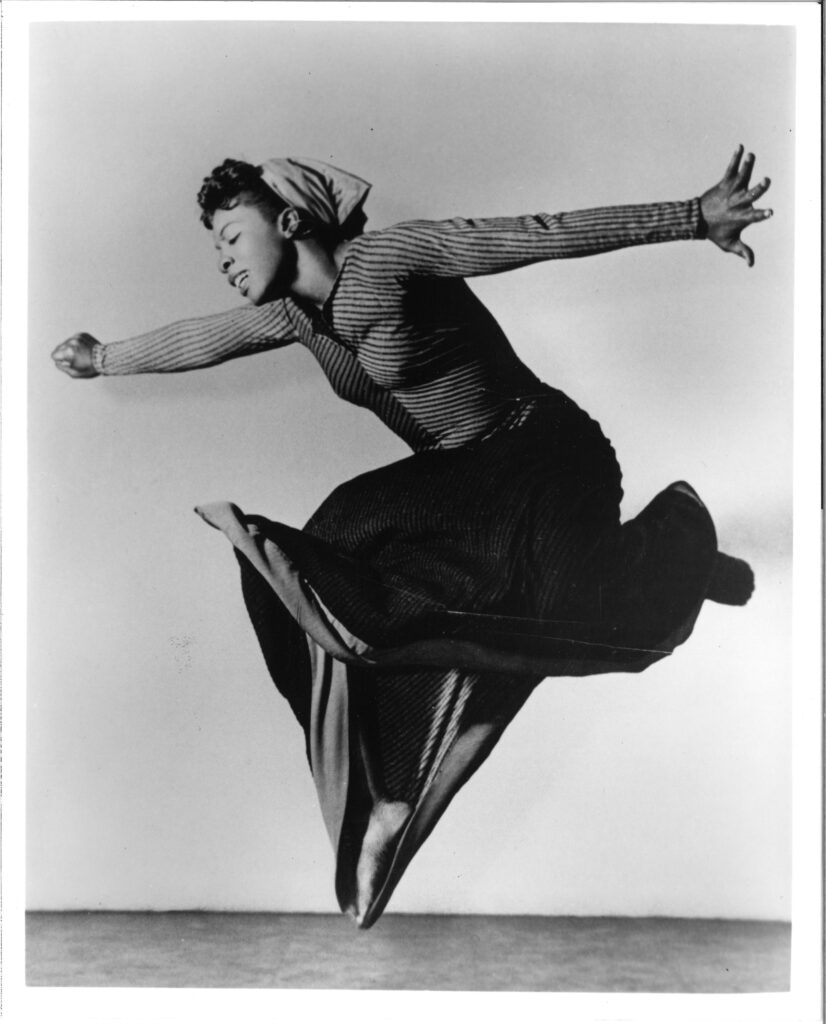 a black and white photo of a woman jumping up in the air