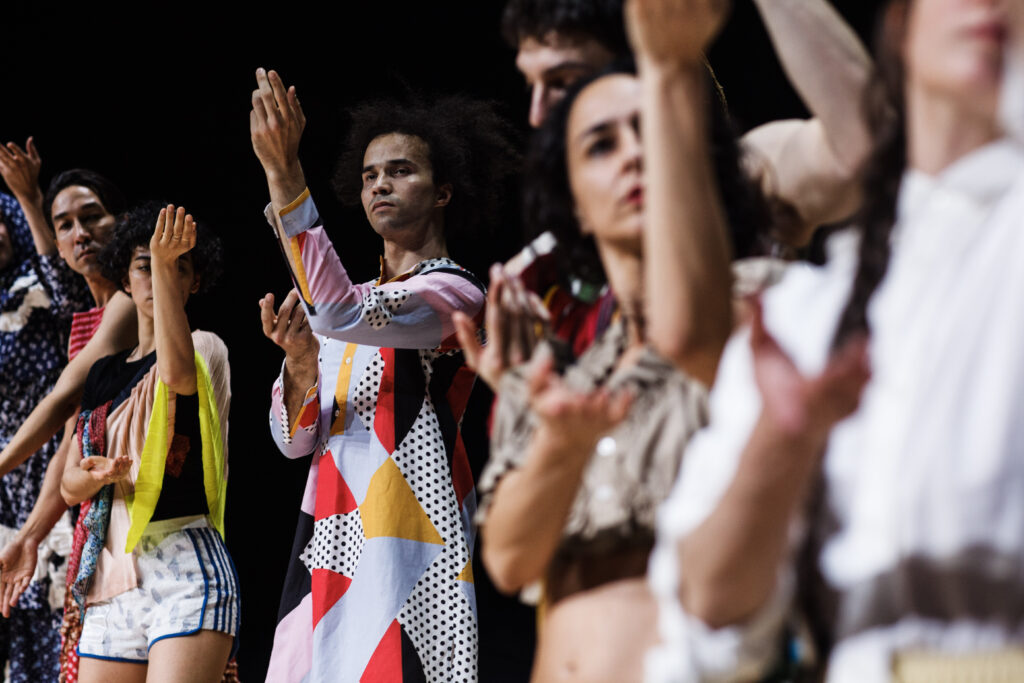 dancers in brightly patterned costumes reaching out