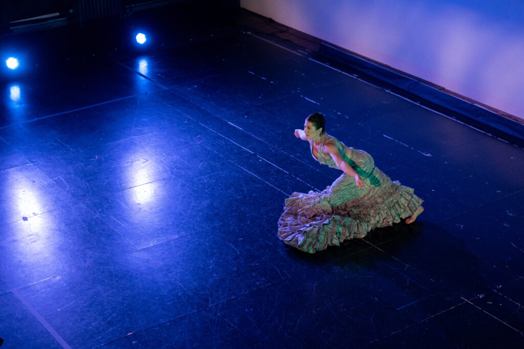 a woman wearing a long dress dancing barefoot on stage 