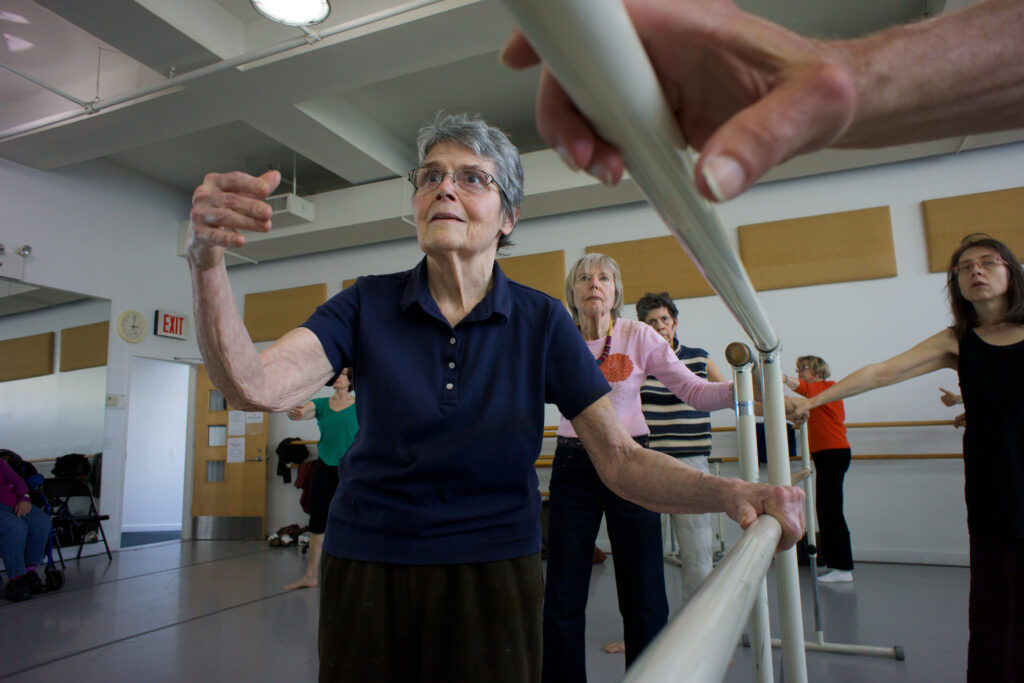 elderly women standing at a ballet barre