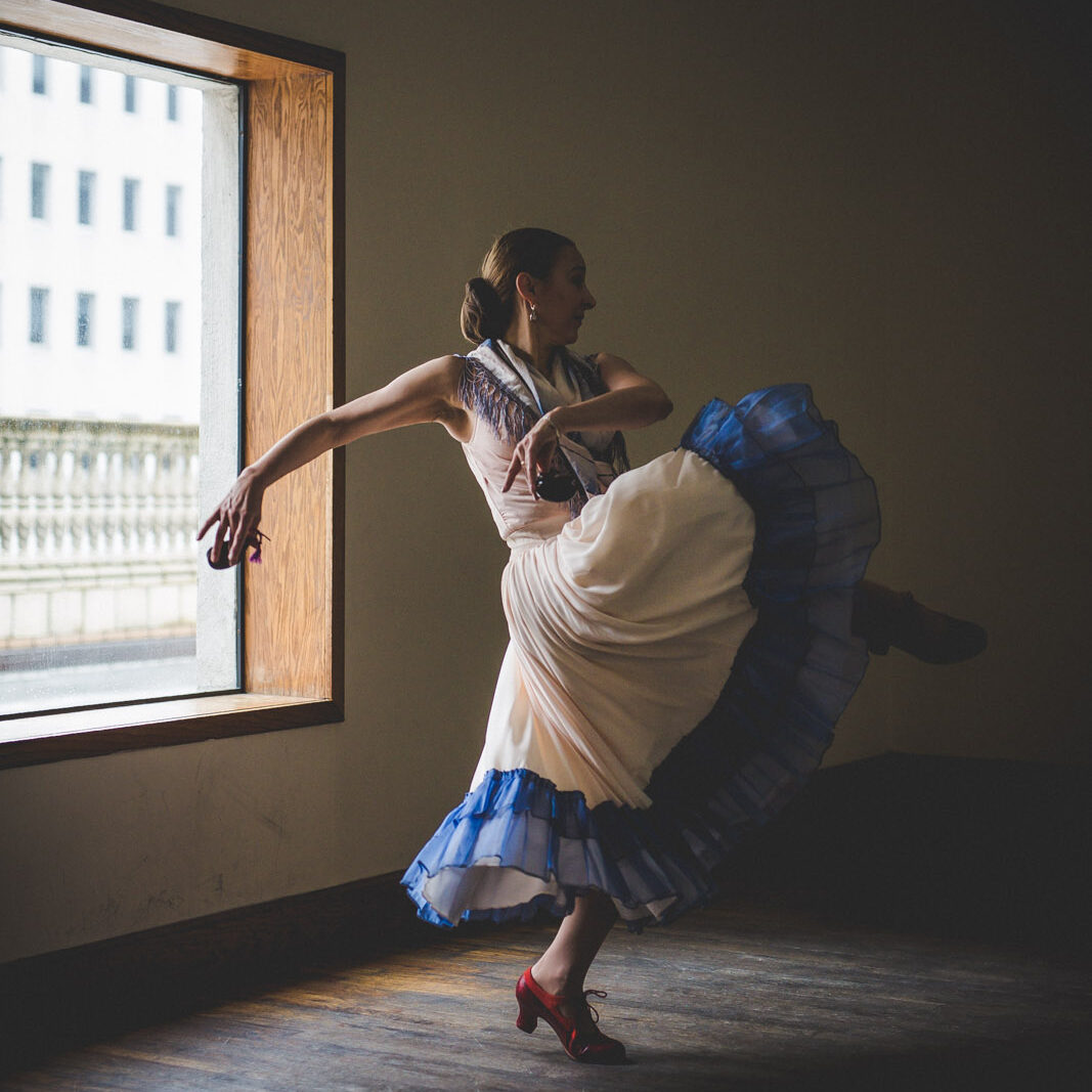 a woman dancing in a studio while wearing a long, flowy blue and white dress