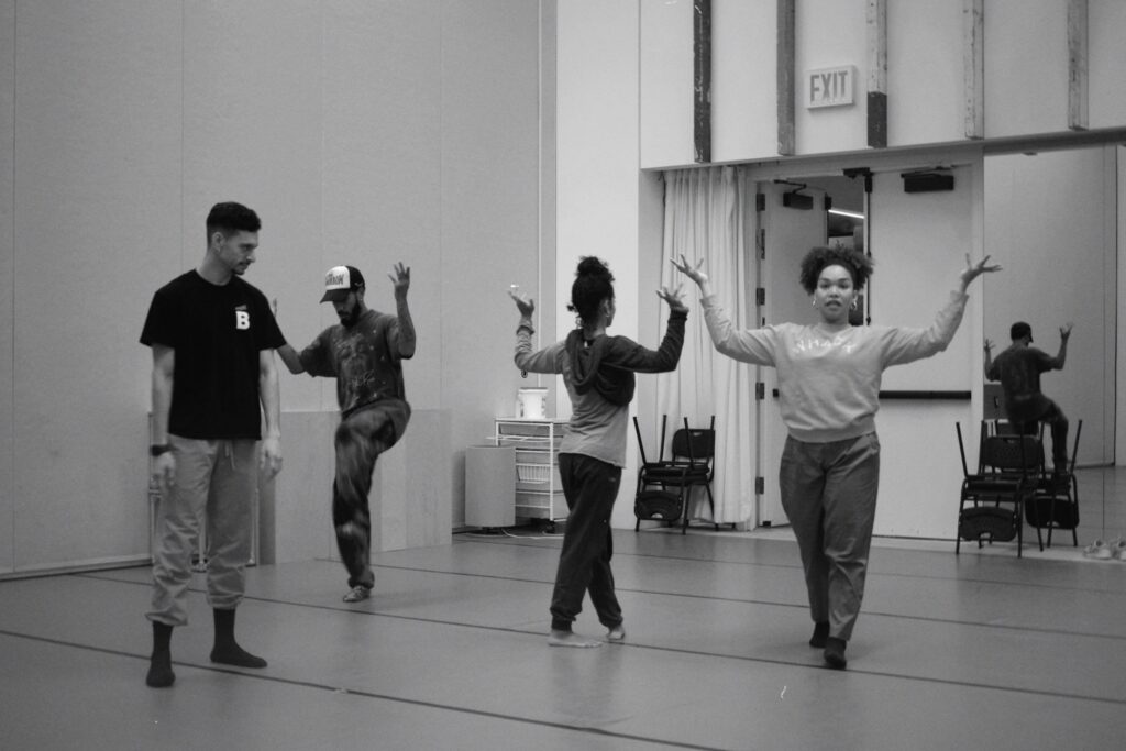 a black and white photo of two men and two women rehearsing in a studio