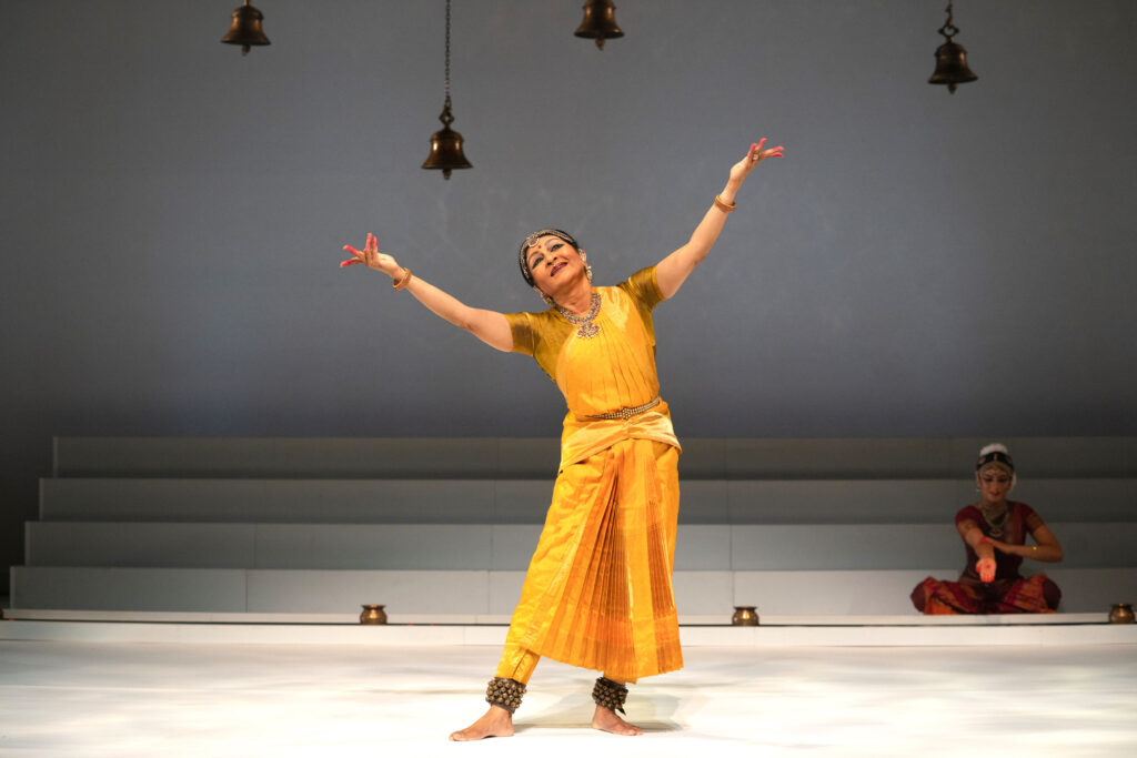 a older woman on stage wearing a traditional yellow dress
