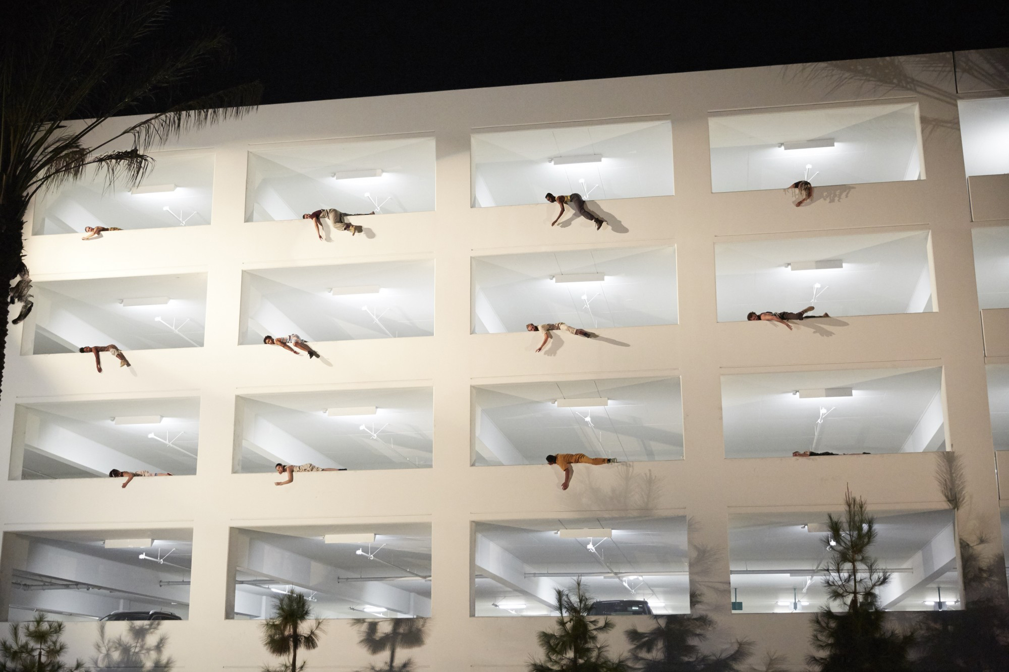 a large parking garage with dancers hanging over the side of each opening