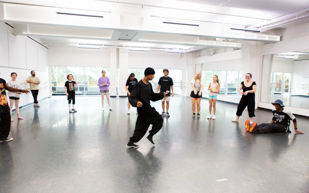 a male instructor teaching hip hop to students in a large studio