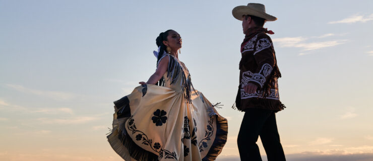 a male and female dancer dressed in western style clothing dancing on an outdoor stage