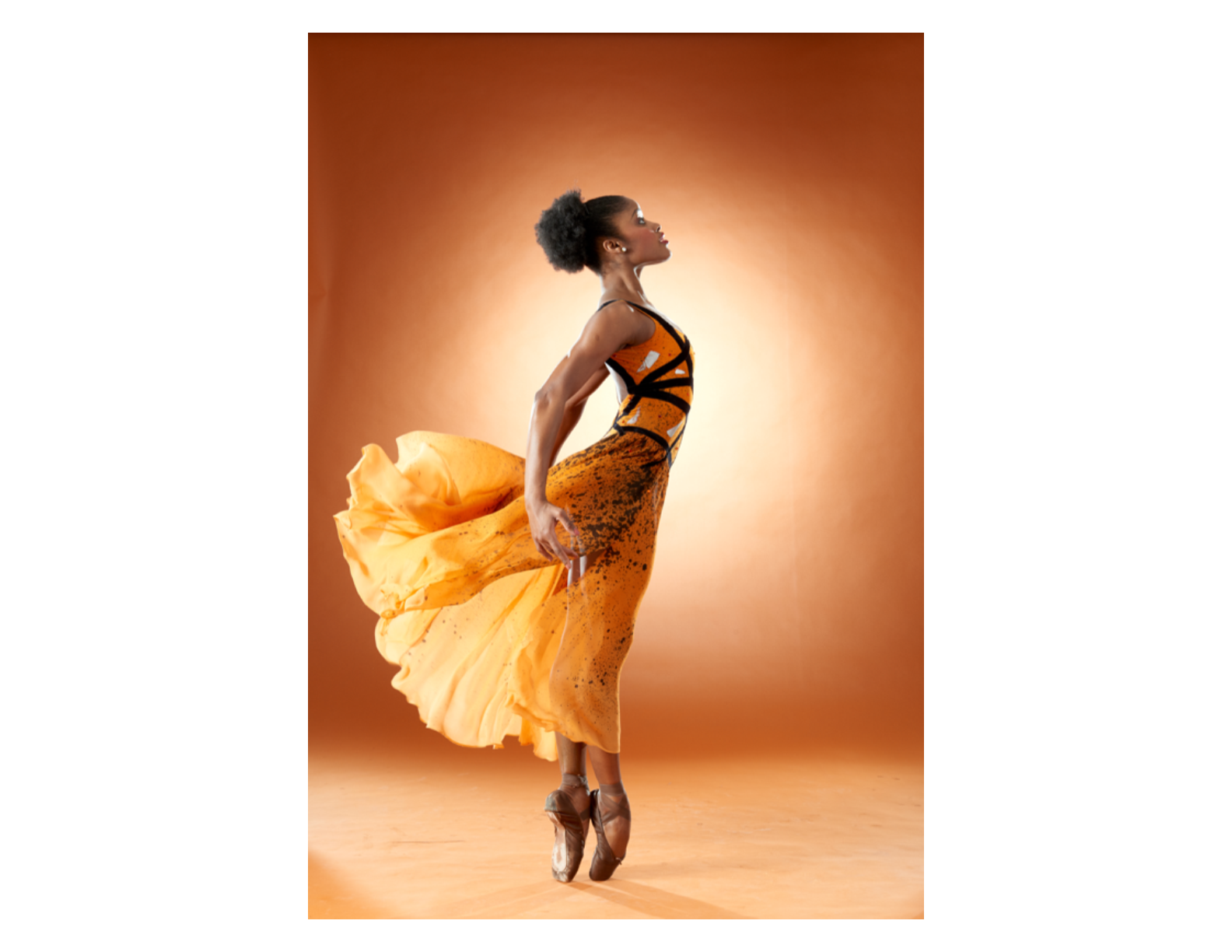 a female dance en pointe posing profile in sous sous while wearing an orange and black dress