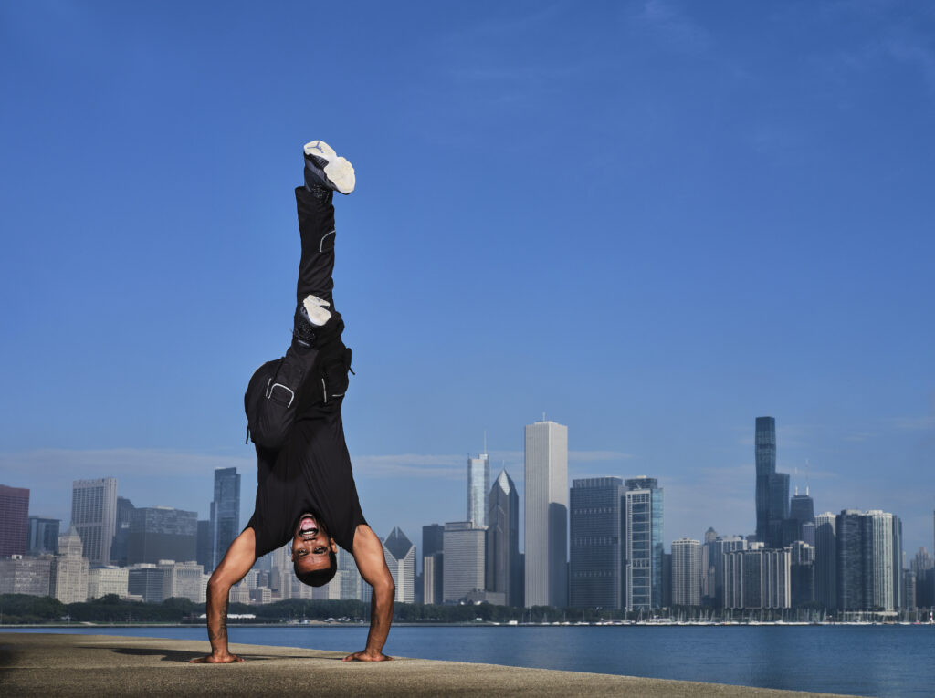 a young man doing a handstand in front of a skyline 