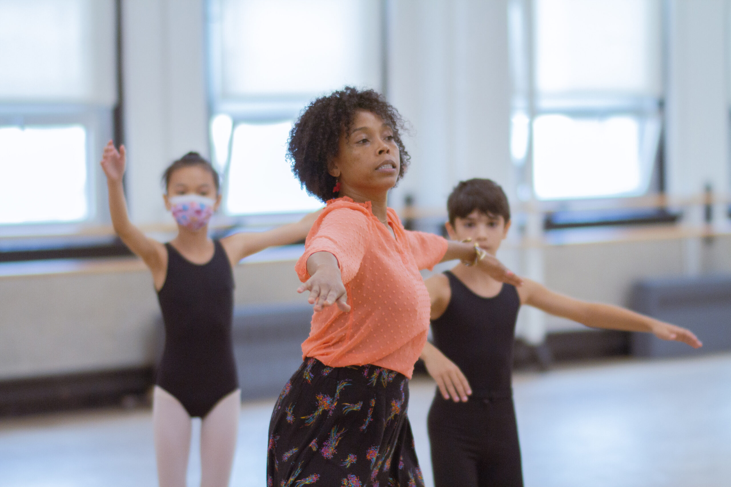 a female instructor leading young dancers in a studio