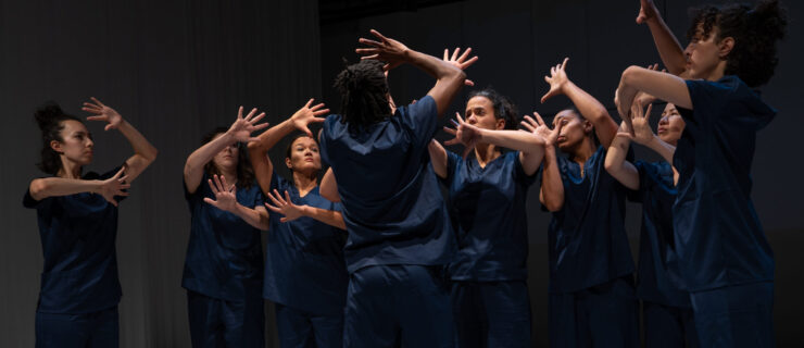 a group of dancers on stage wearing all blue holding their hands outstretched above their heads