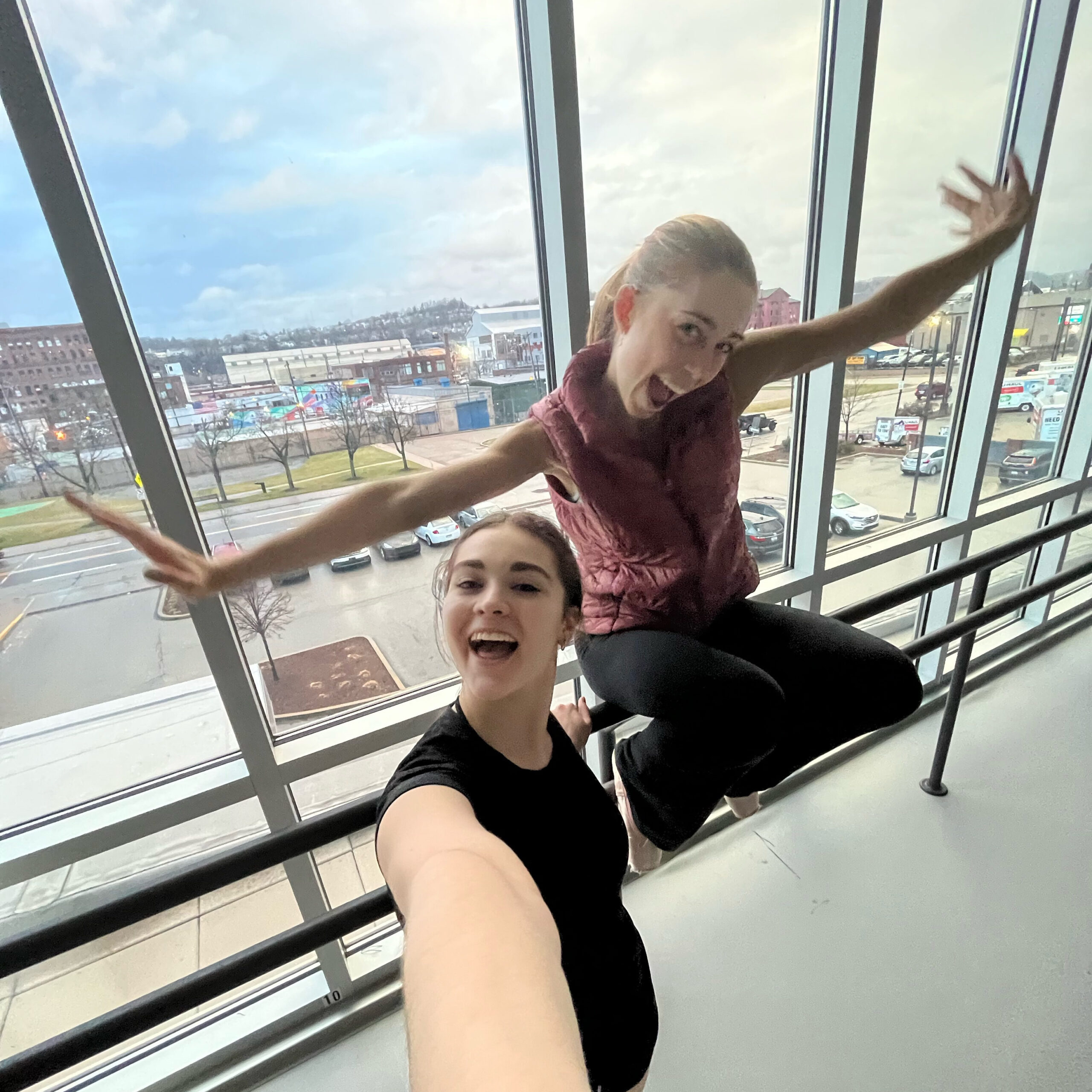 two girls taking a selfie in front of a large window