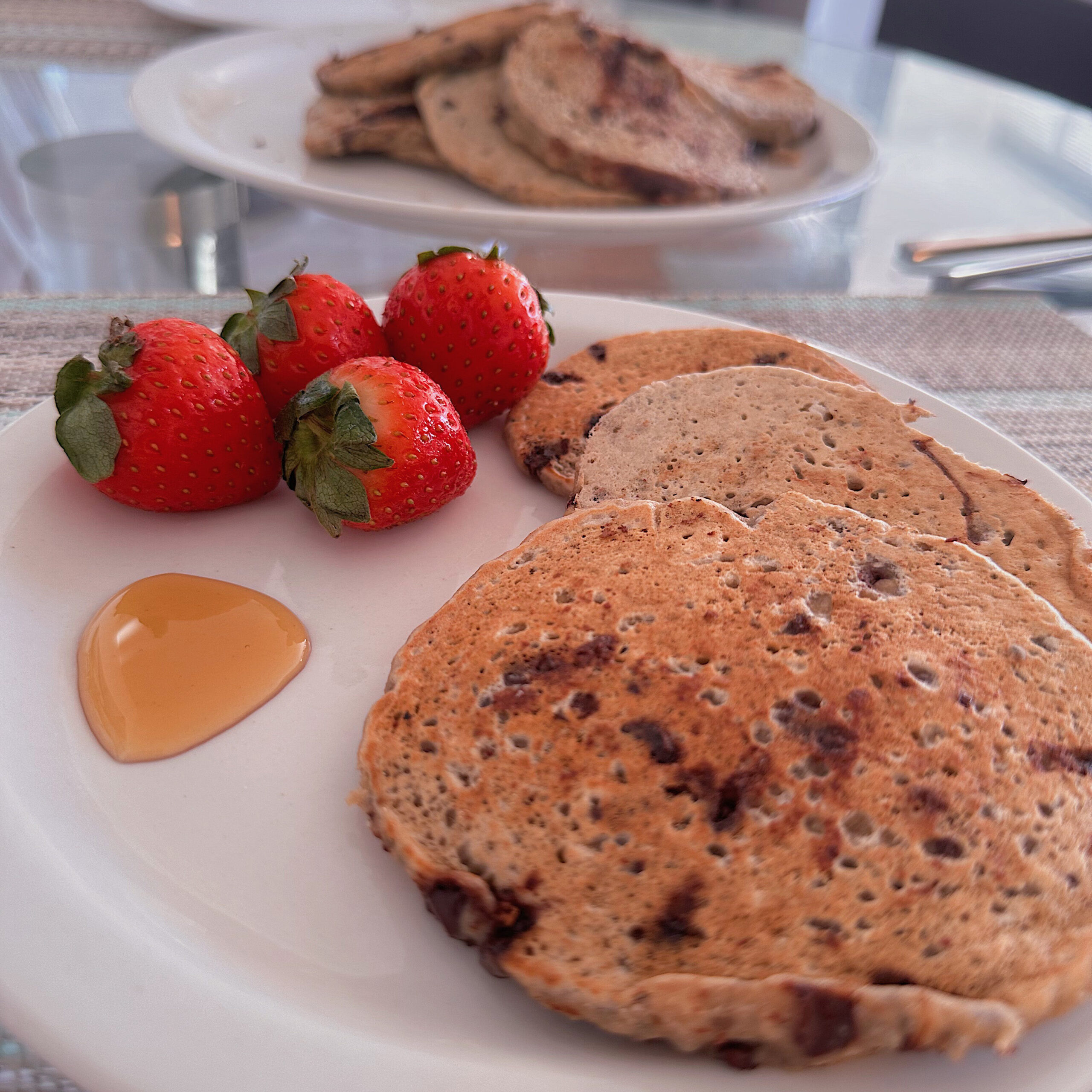 three pancakes sitting on a white plate with strawberries and syrup 