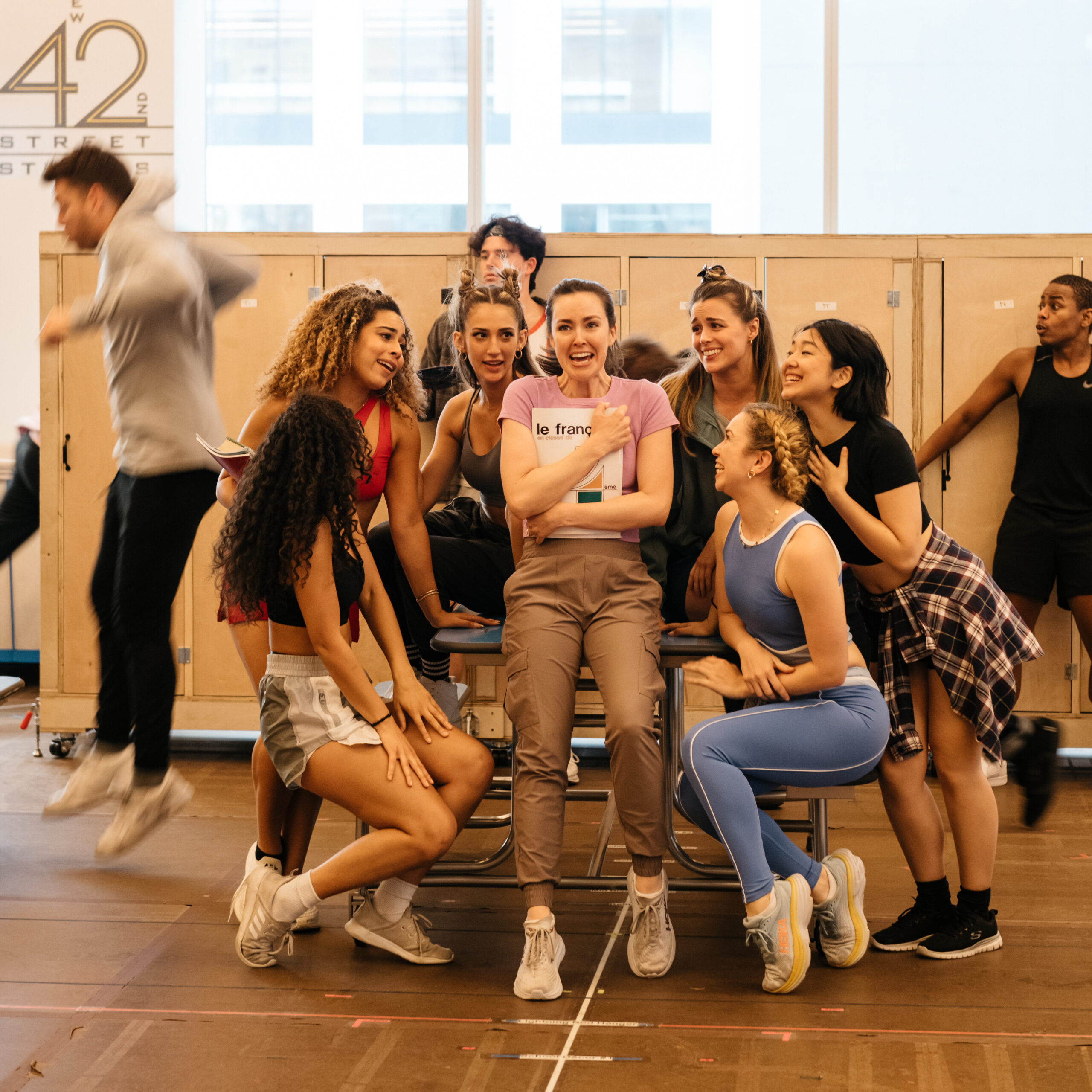 a group of female performers huddled together and staring at the girl in the middle 