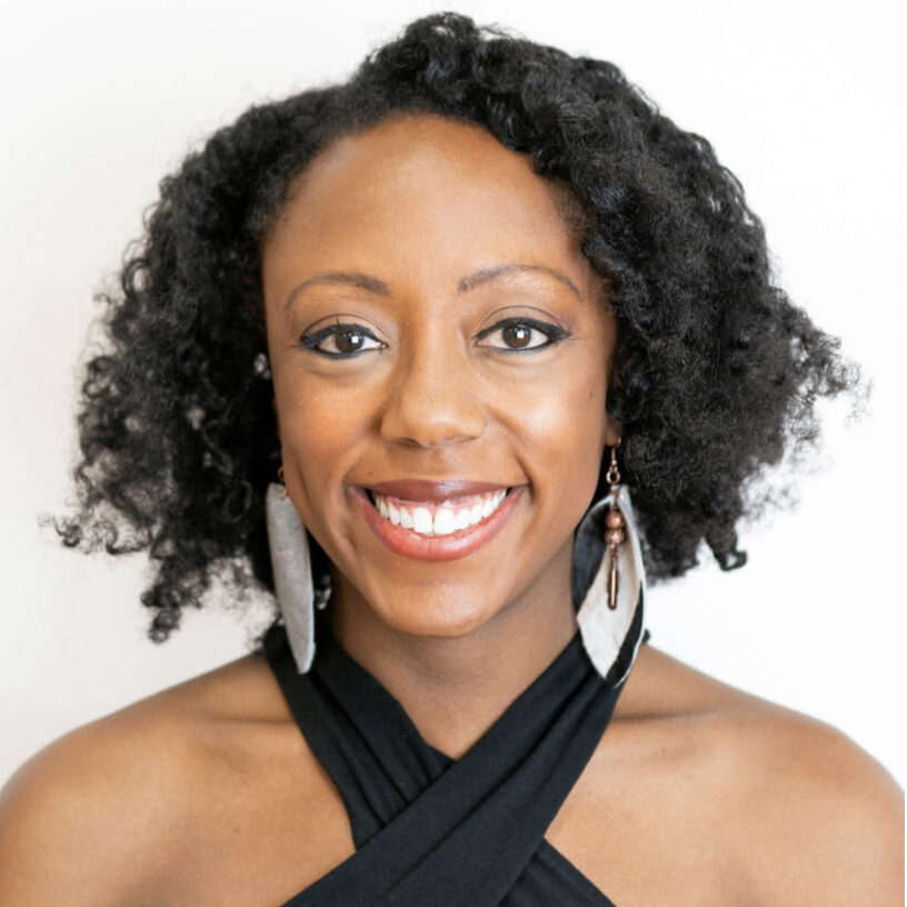 an African-American woman wearing large earrings and a black halter top smiling at the camera