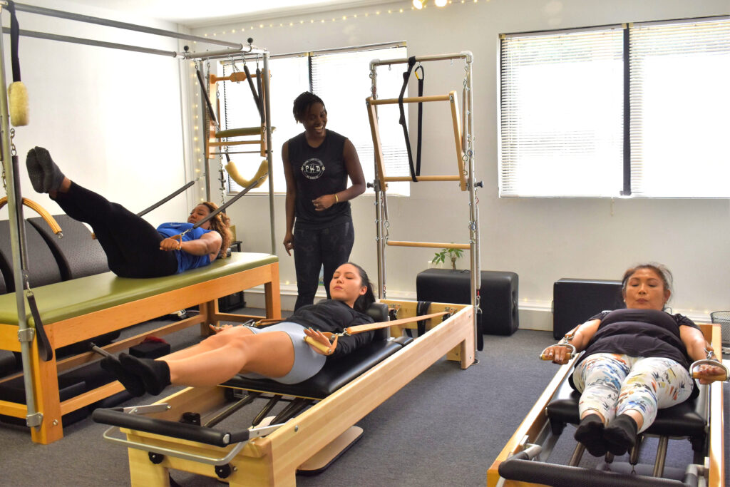 a female pilates instructor leading three females on reformers