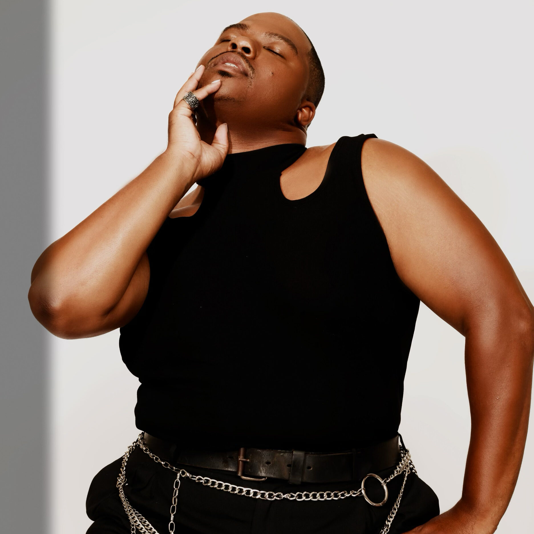 a male dancer wearing all black posing against a white backdrop 