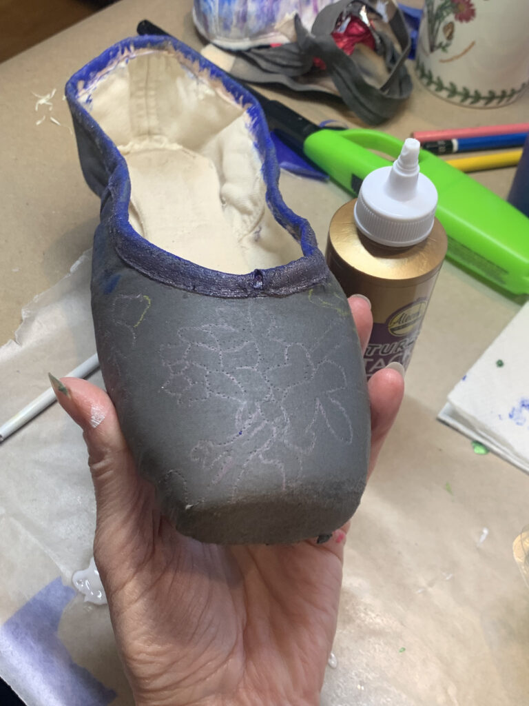 a pointe shoe painted black with a floral design 