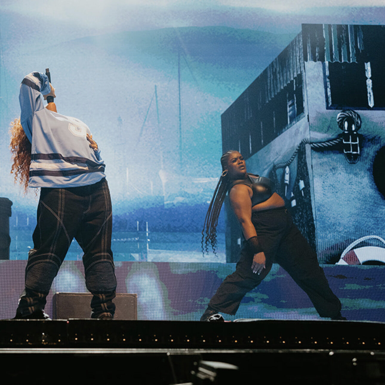 a female dancer wearing all black on stage next to a female singer