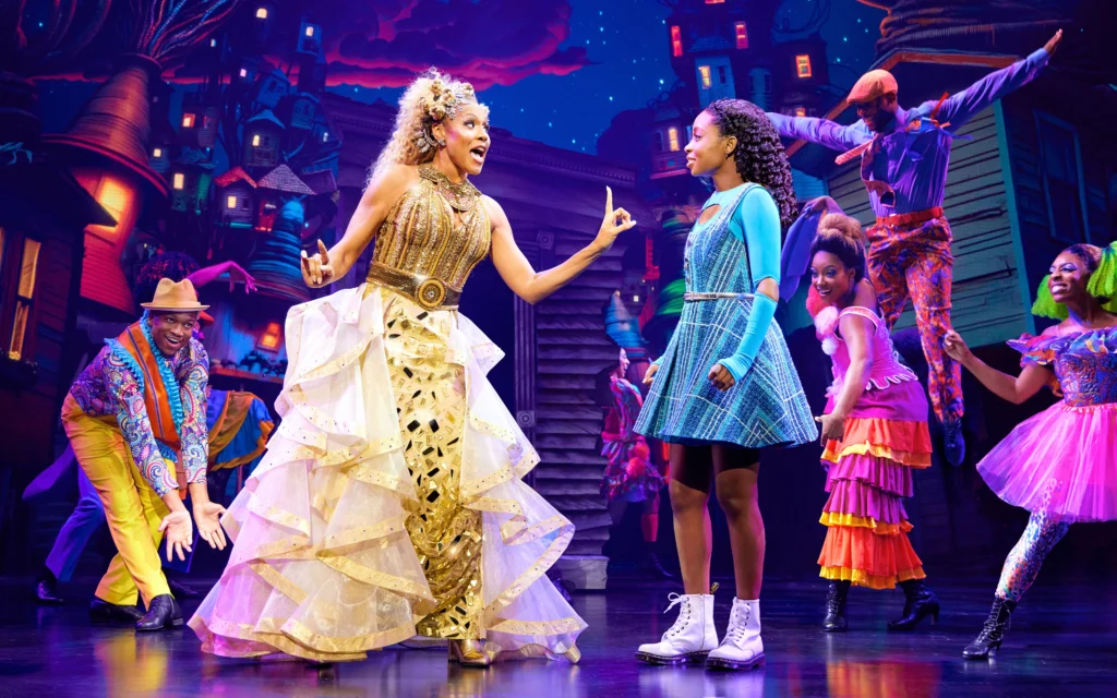 Deborah Cox, resplendent in gold, sings as she holds a cautioning finger up to Nichelle Lewis as Dorothy.