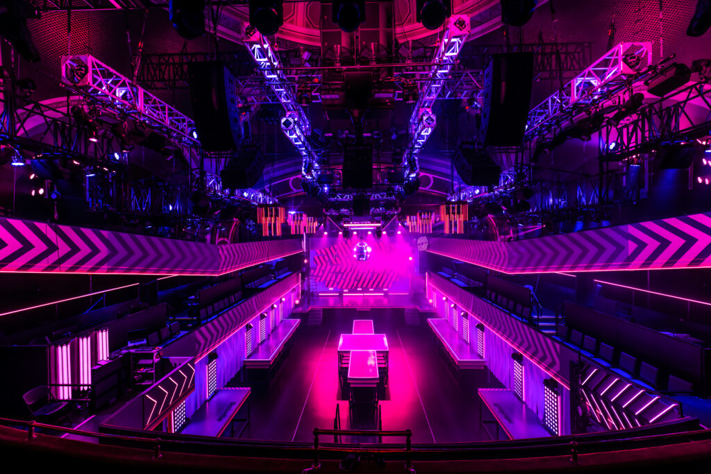 a glowing, pink theater with surrounding lights and platforms around the room