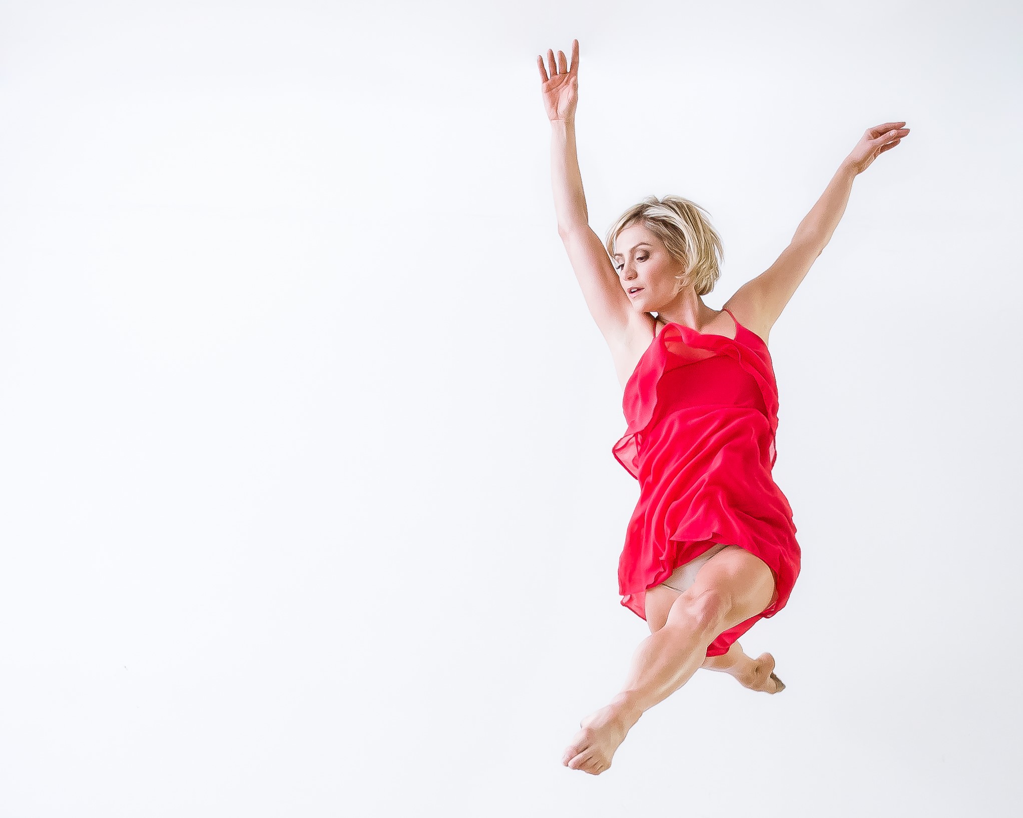 a female dancer wearing a red dress jumping in the air