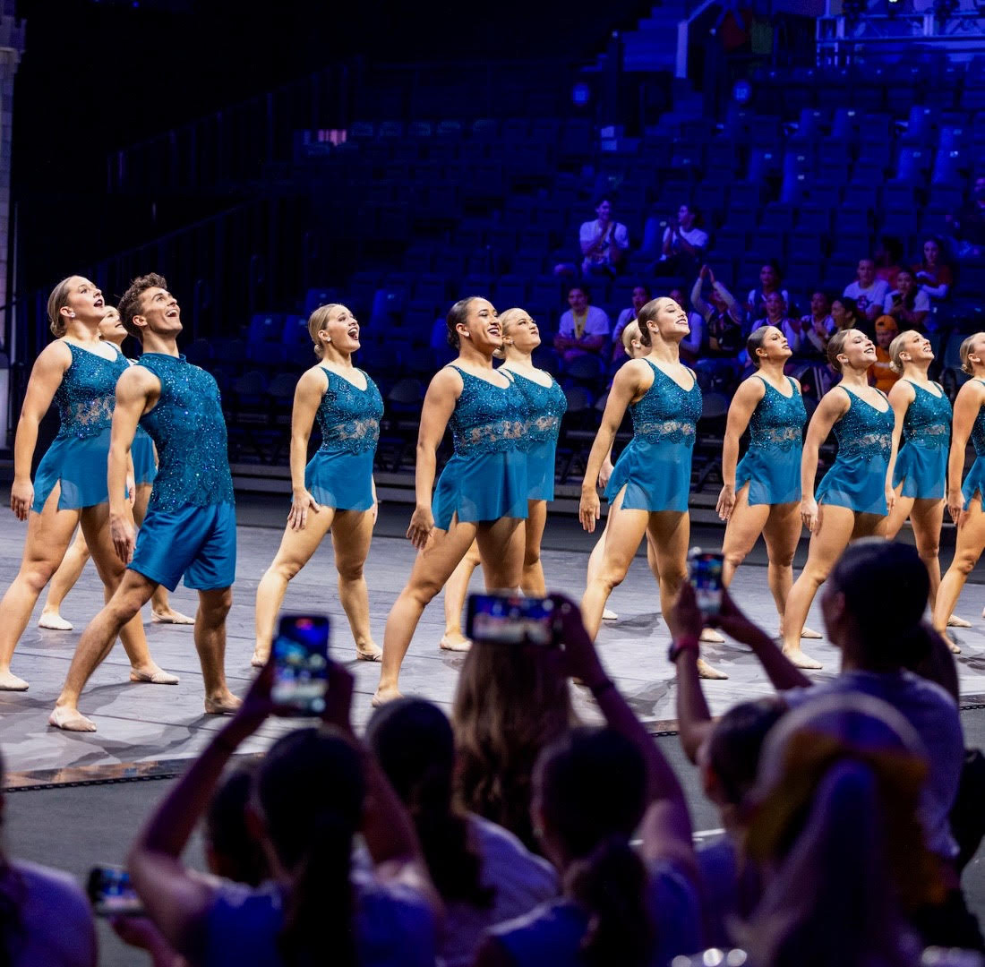 a group of dancers wearing blue standing tall on stage