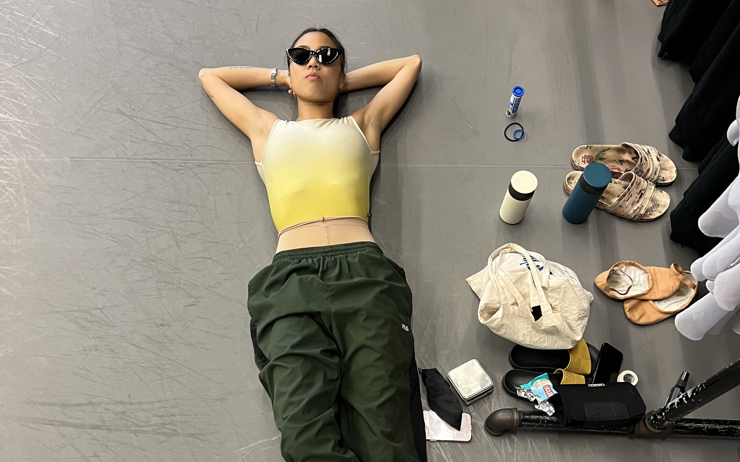 a dancer on the floor wearing dance clothes with dance items on the floor next to her