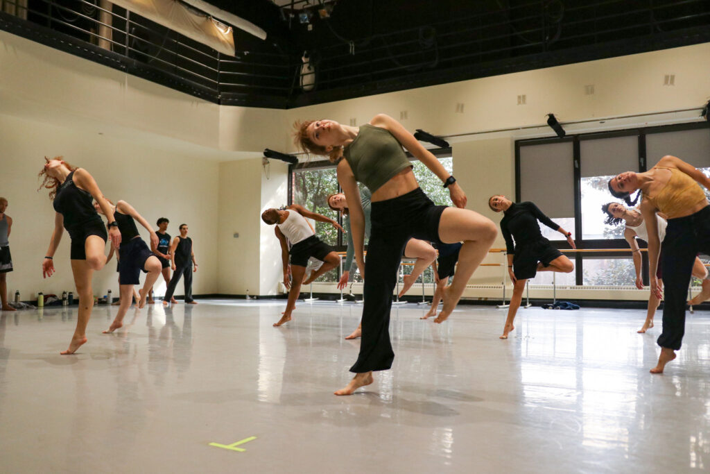 a group of dancers in class leaning to the right and picking up their left leg