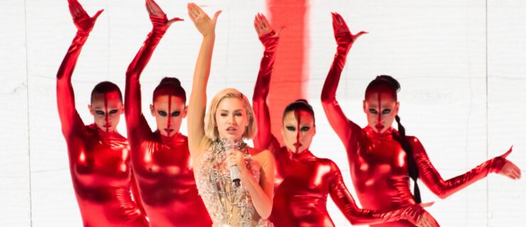 a female pop singer backed up by four female dancers wearing red unitards