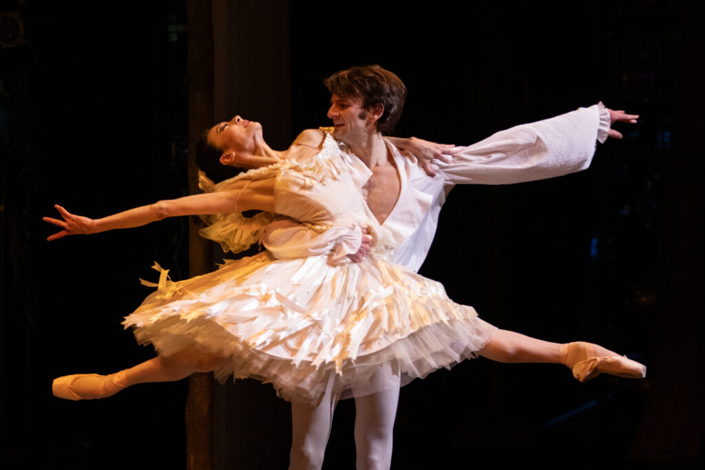 a female dancer in a split being lifted off the ground by a male dancer