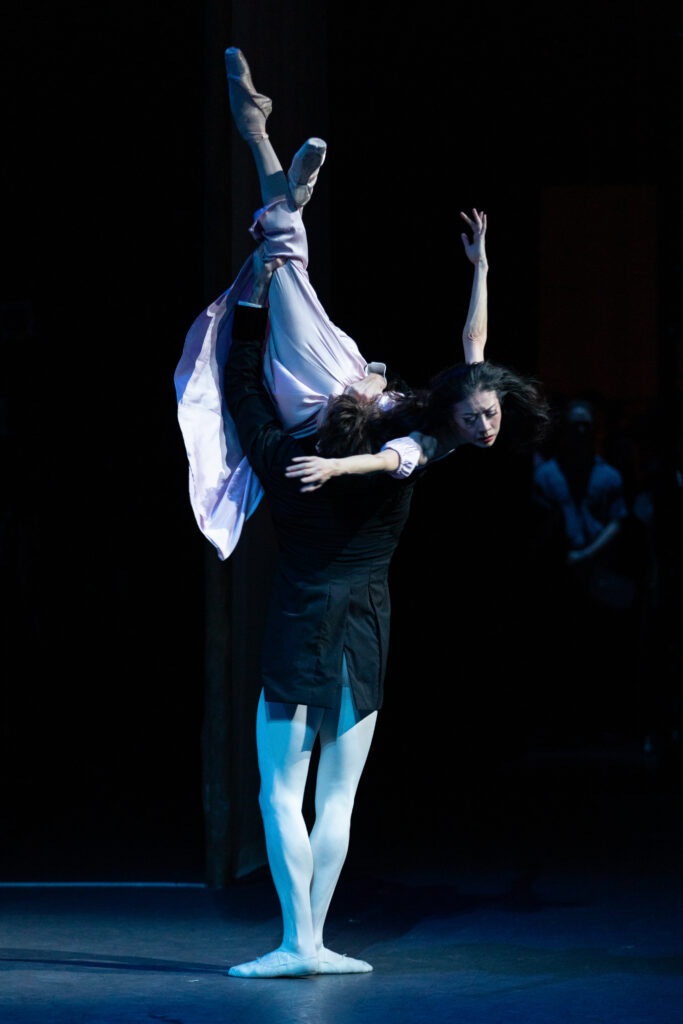 a male dancer supporting a female dancer upside down with her legs lifted high over her head