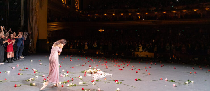 a female dancer bowing center stage with roses all around her