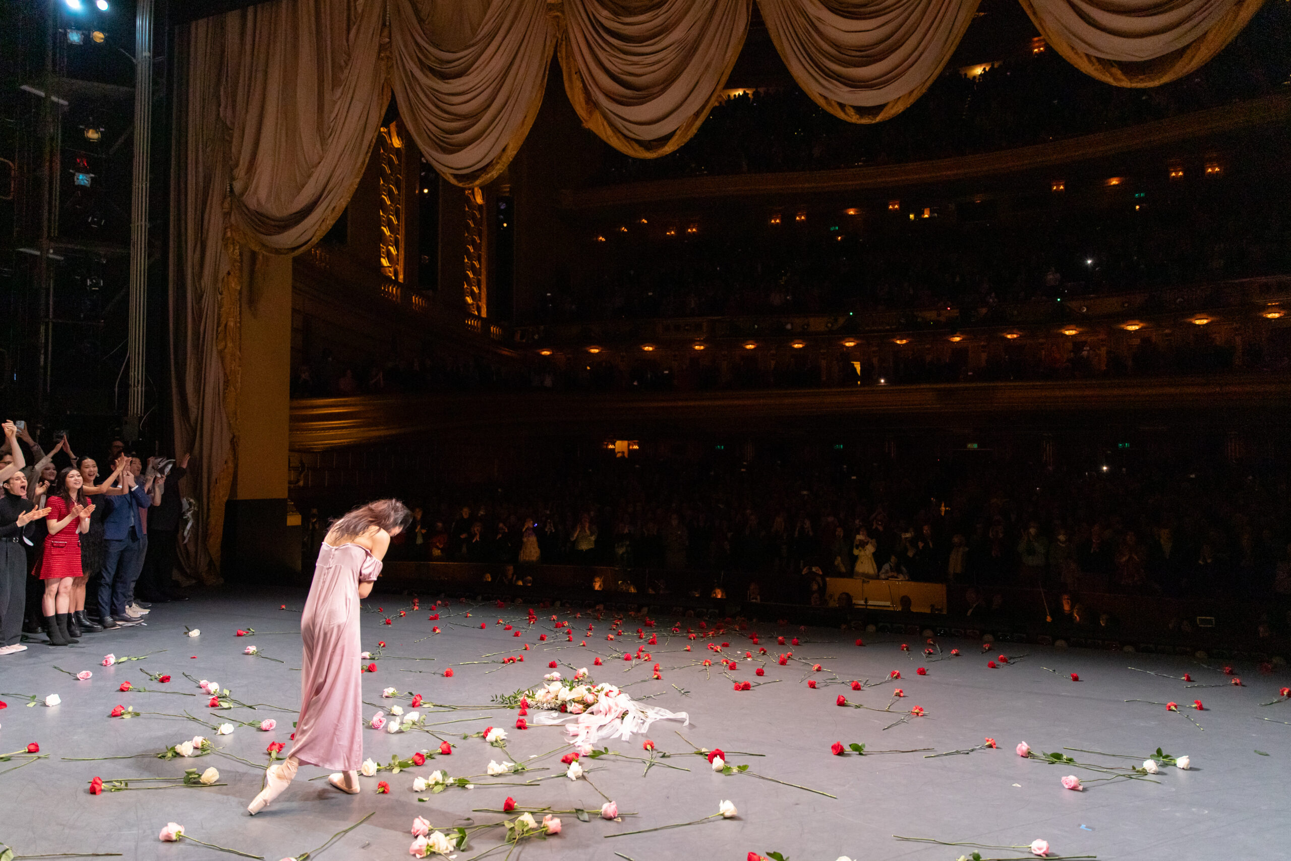 a female dancer bowing center stage with roses all around her