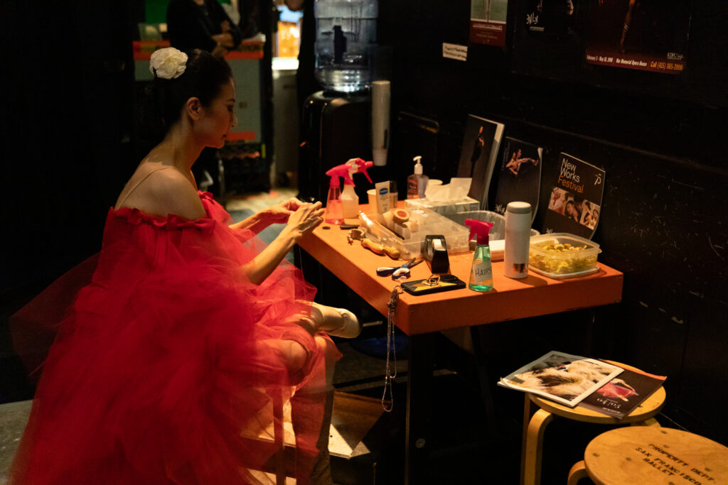 a female dancer sitting at a small table wearing a red tulle costume
