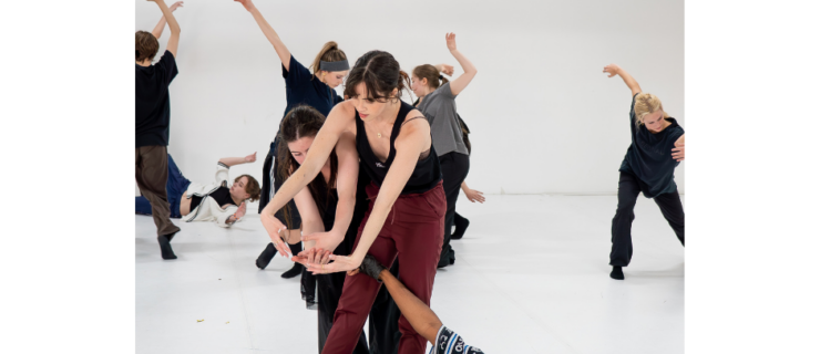 a group of dancers partnering each other in a large white room